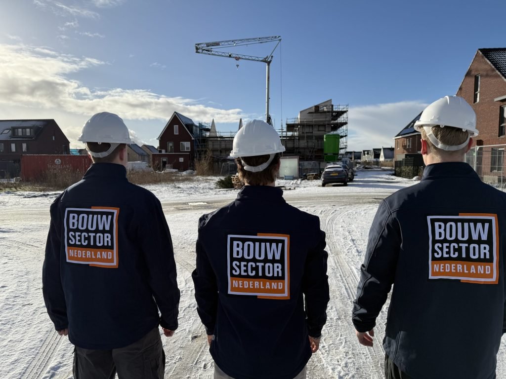 Drie vakmensen van Bouwsector Nederland met witte helm op straat in een woonwijk